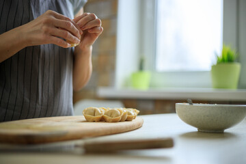 Woman preparing traditional ravioli, putting meat to dough