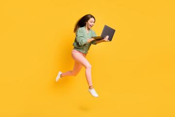 Full size profile side photo of young happy excited amazed girl run in air see big sale in laptop isolated on yellow color background