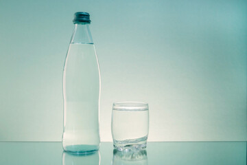 A glass bottle and a glass with clean drinking water are on the table. Copy space.