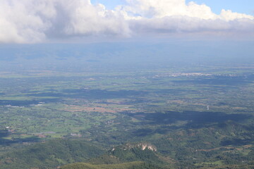 Naklejka premium Scenery shot from the top of a high mountain with a cool breeze. Above there were large clouds gathering. Below are many green trees. And there are shadows from the clouds. Take photo in Thailand.