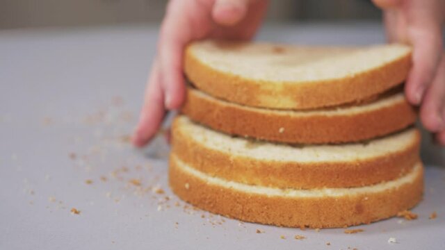 The pastry chef demonstrates the neatly sliced layers of sponge cake for the cake. The pastry chef puts a stack of neatly sliced layers of sponge cake in a row. High quality 4k footage