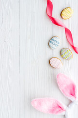 Top view of Easter bunny ears with eggs cookies, space for text