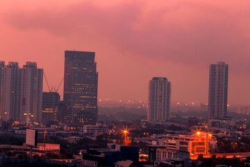 Obraz premium The high angle background of the city view with the secret light of the evening, blurring of night lights, showing the distribution of condominiums, dense homes in the capital community
