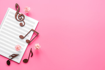 Musical wooden notes on music sheet with flowers. Top view