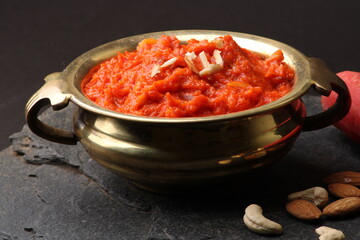 Gajar ka halwa is a carrot-based sweet dessert pudding from India. Garnished with Cashew almond nuts and Served in brass bowl.