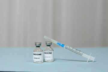 ampoule with a vaccine against coronavirus and syringe on blue surface, vaccination of covid-19, health care concept