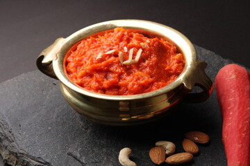 Gajar ka halwa is a carrot-based sweet dessert pudding from India. Garnished with Cashew almond nuts and Served in brass bowl.