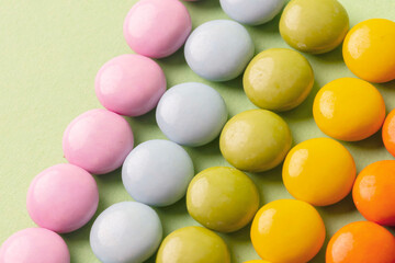 Image of chocolate candy or colorful pills. On a green surface. Neatly arranged image.