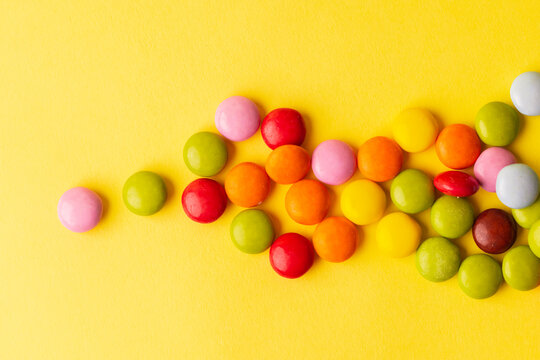Image of chocolate candy or colorful pills. On a yellow surface