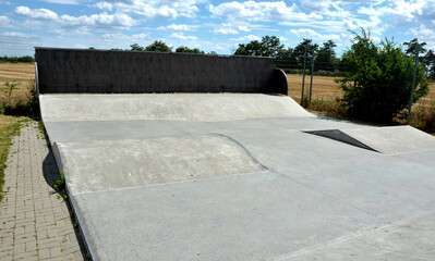 concrete skateboard playground in a fenced area outside the city. Railing ramps are for beginners...