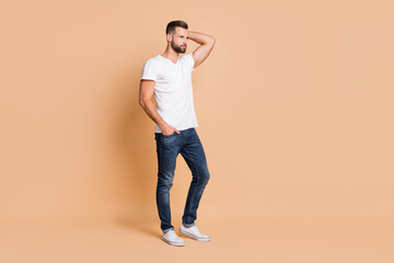 Full size photo of young attractive serious confident man look empty space hand in pocket isolated over beige color background