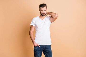 Photo of young handsome bristle man confident serious hand in pocket isolated over beige color...