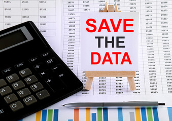 Save The Date on small easel with charts, pen and calculator.Business concept.
