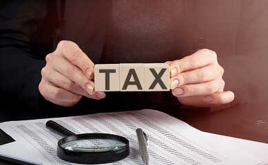 businesswoman holding wooden block with text TAX , business concept