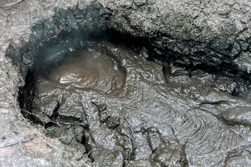Boiling mud pools in volcanic landscape