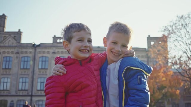 Two cheerful friends are hugging. Brothers for a walk in the autumn park. Best friends. Family vacation, family video. Childhood concept.