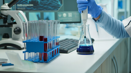 Close up of scientis testing liquid sample late at night using micropipette for medical treatment...