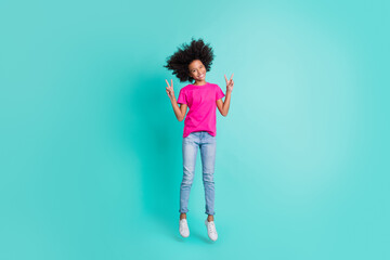 Full size photo of young happy positive good mood smiling girl jumping showing v-sign isolated on teal color background