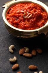 Gajar ka halwa is a carrot-based sweet dessert pudding from India. Garnished with Cashew almond nuts and Served in brass bowl.