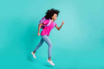 Photo portrait full body side profile view of running black skin schoolgirl jumping up isolated on vivid cyan colored background