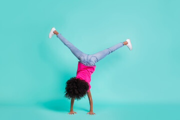 Full length photo portrait of black skin girl standing on hands isolated on vivid cyan colored...