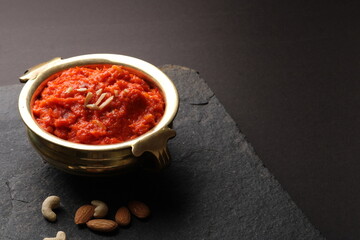 Gajar ka halwa is a carrot-based sweet dessert pudding from India. Garnished with Cashew almond nuts and Served in brass bowl.