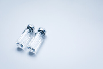 Two glass bottles with liquid on gray background with copy space. The medical conception of combating the covid-19 pandemic. Flu vaccination.  Flat lay
