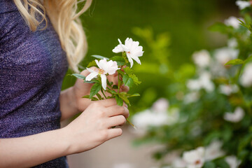 Beautiful girl holding blossoming branch of white flowers In her hands. Close up. Spring time. Copy space