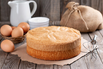 Wrapping sponge cake in plastic for storing on wooden table
