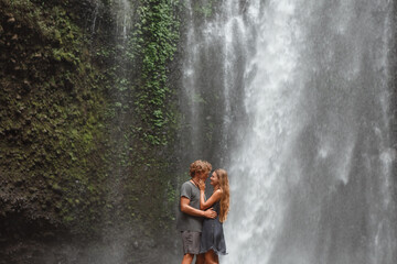Young traveling couple explore waterfall in Bali, love story, people in love, vacation in Asia