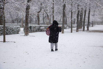 a hard worker woman going to work through a snowstorm in a camp with her red bag at winter