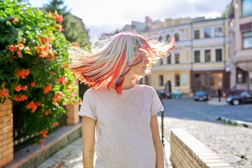 Close-up of fluttering colored dyed hair of young woman on sunny city street