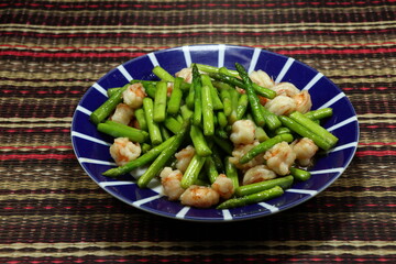 Traditional fried organic asparagus with fresh peeled shrimp serving on the plate. Famous classic seafood menu in Asian restaurant. 