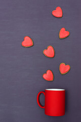 Valentine's Day, red heart shaped cookies on purple paper background flying vertically from a red mug, flat lay. Love and Valentine's Day concept.
