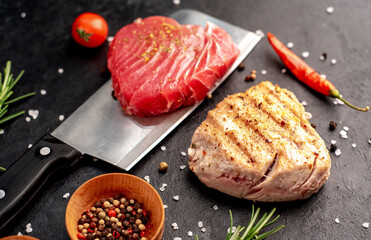 Raw tuna steak on a knife and grilled tuna steak in the shape of a heart with rosemary and spices...