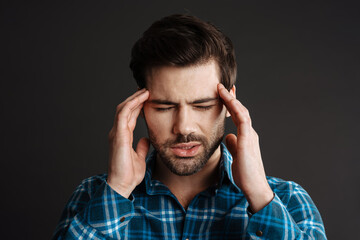 Naklejka premium Unhappy handsome unshaven guy with headache rubbing his temples