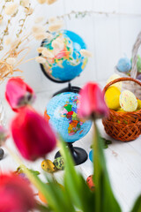 Easter eggs and globe on a white wooden background