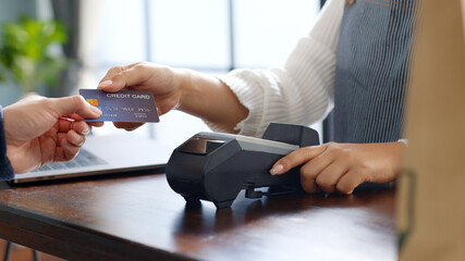 Customer using credit card for payment to owner at cafe restaurant, cashless technology and credit card payment concept