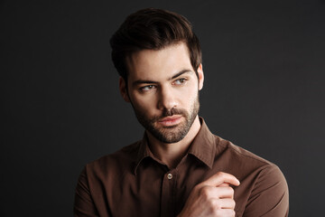 Brunette handsome unshaven guy posing and looking aside