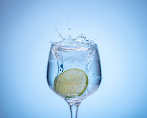 Fototapeta na wymiar glass of water with lemon droped in and splash