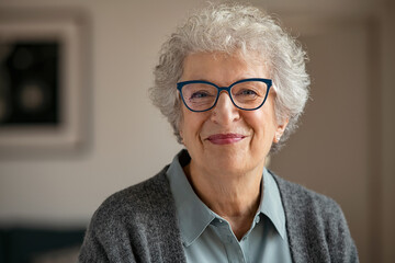 Senior smiling woman with spectacles looking at camera - obrazy, fototapety, plakaty