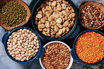 Various assortment of legumes beans, chickpeas, lentils, green peas. Healthy eating concept. Vegetable proteins. concrete background copy space top view