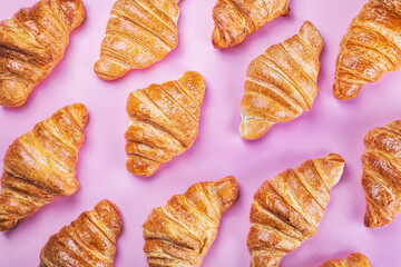 freshly baked croissants lie on a pink background
