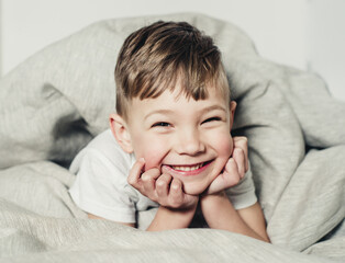 happy and cheerful boy lies in bed