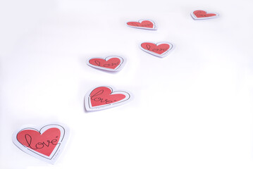 Paper hearts with "love"  written on them, flying like butterflies, on a white background. Concept of love, Valentine  