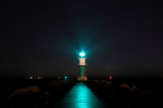 Leuchtturm Westmole grün in Warnemünde mit Sternenhimmel bei Nacht 