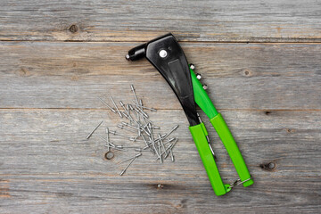 Rivet gun. A rivet gun on a gray wooden table in close-up. The rivet gun and rivets are on the desktop