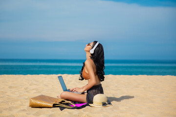 Young asia woman using a laptop computer on a beach. Freelance work concept and holiday working or money passive income