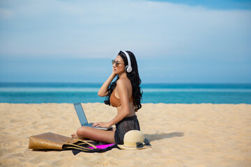 Young asia woman using a laptop computer on a beach. Freelance work concept and holiday working or money passive income