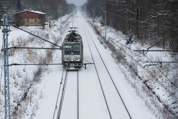 Lokomotywa elektryczna jadąca po torach pokrytych śniegiem. © boguslavus